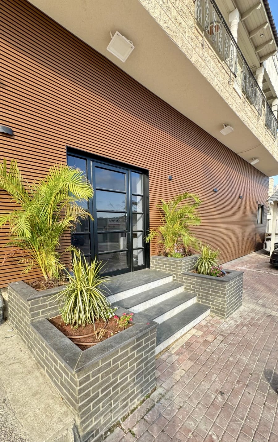 כניסת עסק עם דלת זכוכית ומסגרת אלומיניום שחורה וחיפוי קיר