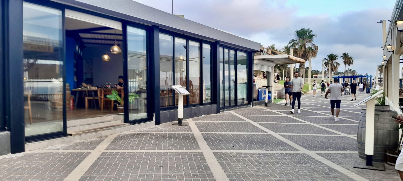 חזית זכוכית ודלתות הזזה מאלומיניום לבית קפה על טיילת חוף הים